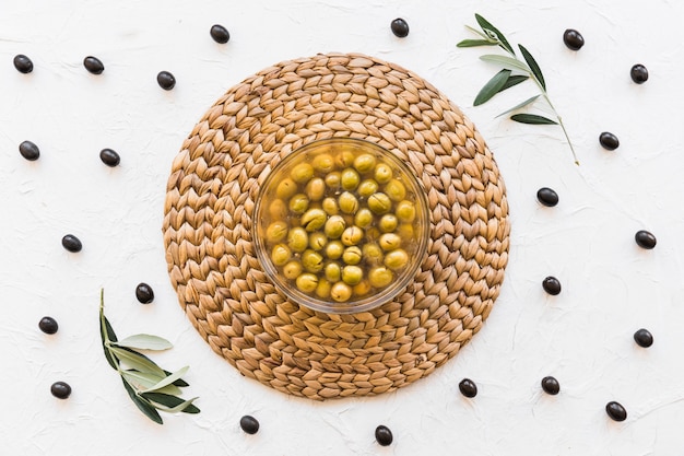 Free photo bowl with olives and oil on corset with white backdrop