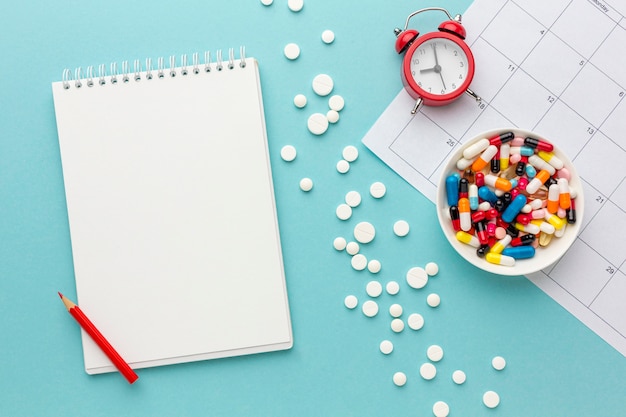 Free photo bowl with pills and clock beside on desk