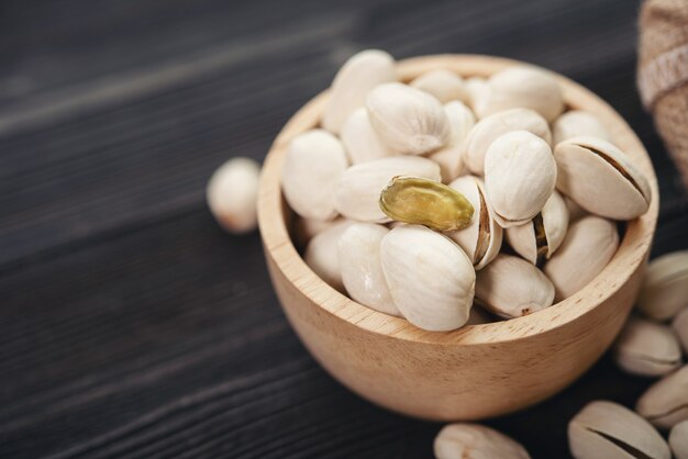 Bowl with pistachios on a wooden table.