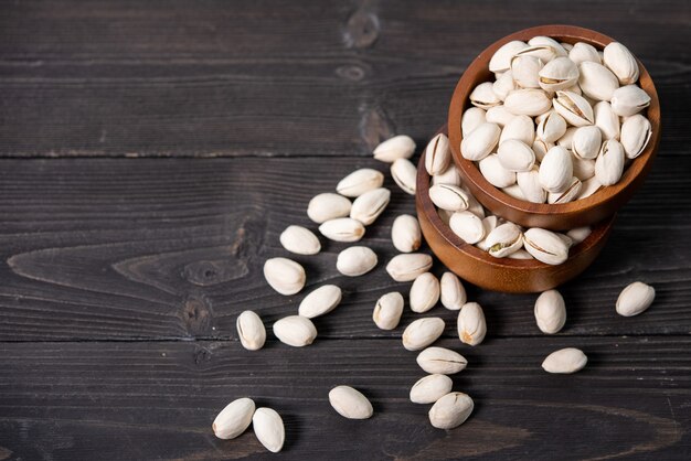 Bowl with pistachios on a wooden table.