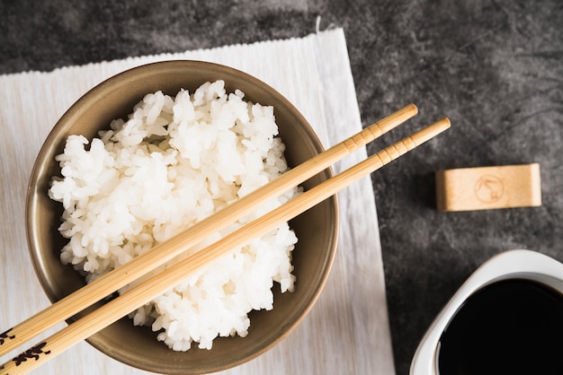 Bowl with rice and chopsticks on napkin near soy sauce