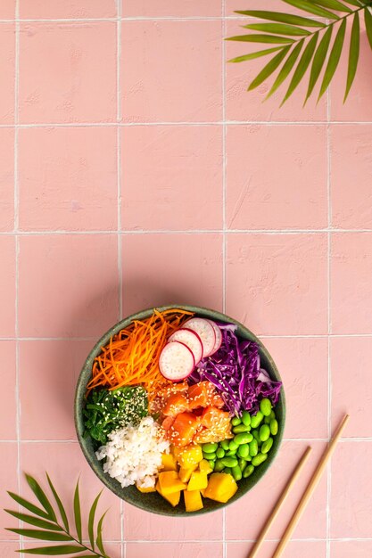 Bowl with salmon rice and fresh vegetables poke top view Vertical