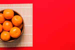 Free photo bowl with tangerines on bamboo napkin