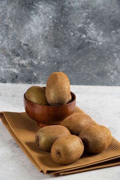 Bowl with tasty kiwi fruits on brown tablecloth 