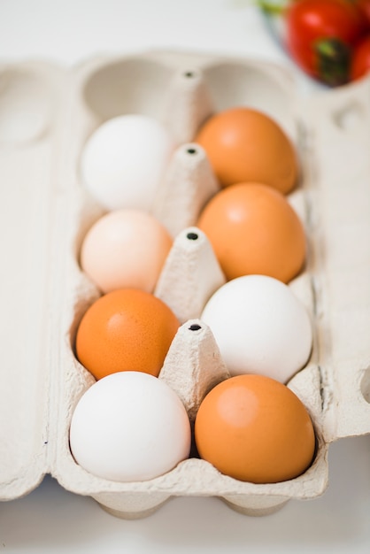 Free photo box of eggs on table near tomatoes