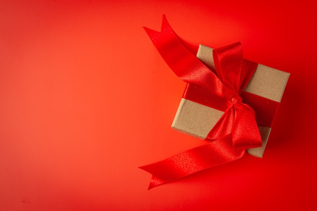 Free photo box of present with red ribbon bow on red background