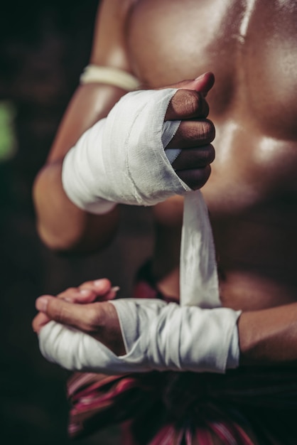 Free photo the boxer sat on the stone, tied the tape around his hand, preparing to fight.