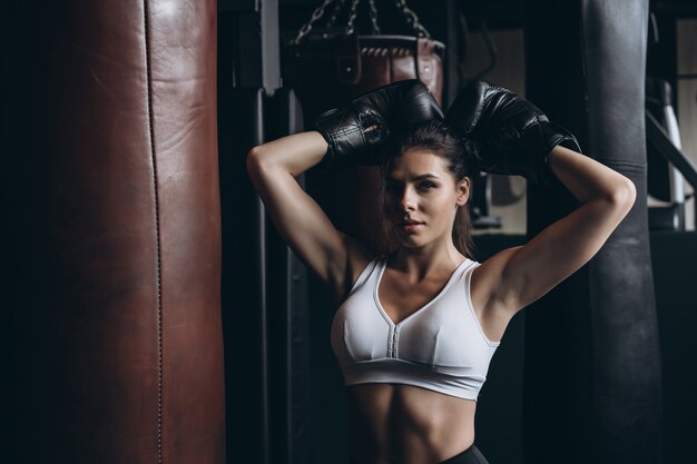 Boxing woman posing with punching bag, on dark . Strong and independent woman concept