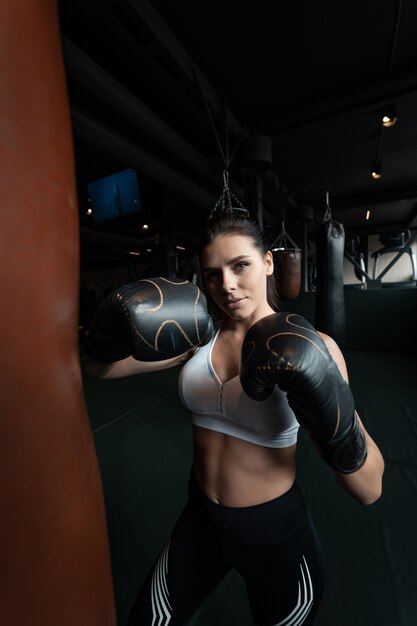 Boxing woman posing with punching bag. Strong and independent woman concept