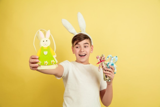 Free photo boy as an easter bunny on yellow studio wall