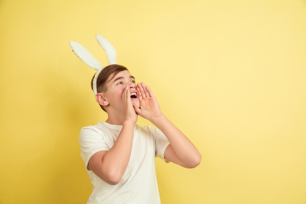 Free photo boy as an easter bunny on yellow studio wall