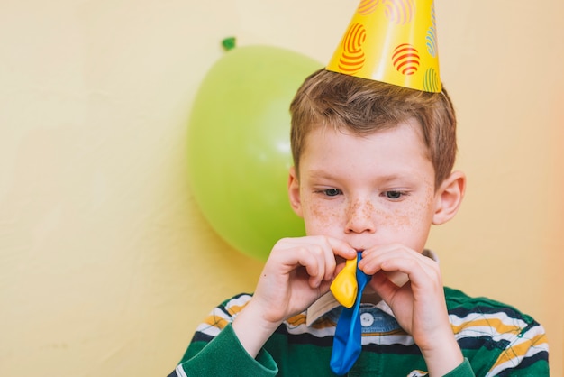 Free Photo boy blowing up balloons for birthday party