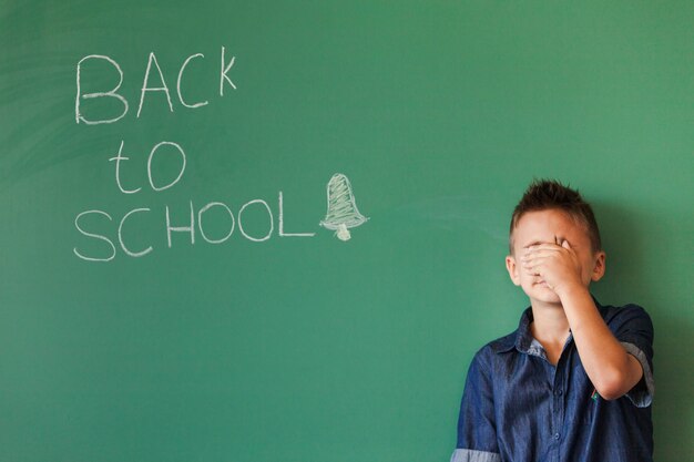 Boy closing face in classroom