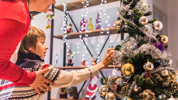 Free photo boy decorating christmas tree