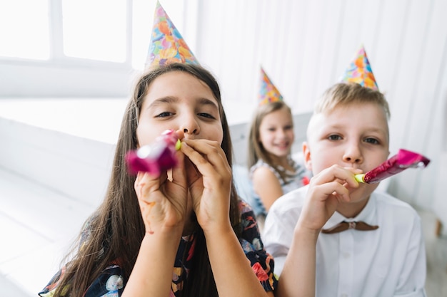 Boy and girl blowing party horns at camera