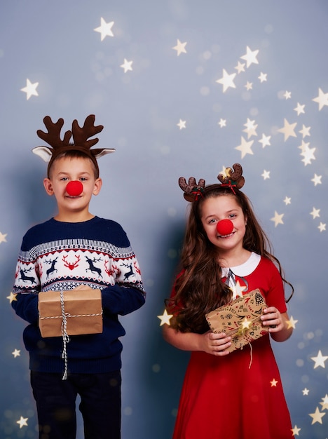 Free photo boy and girl with reindeer antler holding gift box