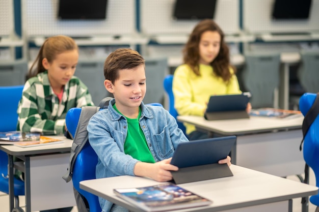 Boy and girls sitting at desk looking at tablet