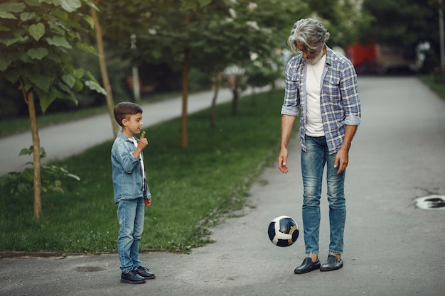 Boy and grandfather are walking in the park. Old man playing with grandson. Family playing with a ball.