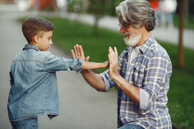 Free photo boy and grandfather are walking in the park. old man playing with grandson.