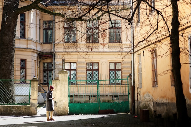 Boy in grey coat and red hat stands on the street 