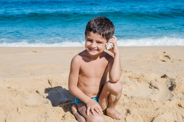 Free photo boy hearing through a shell