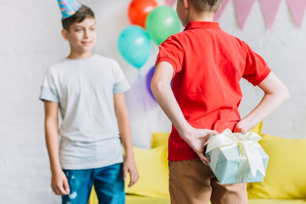 Boy hiding birthday gift from his friend