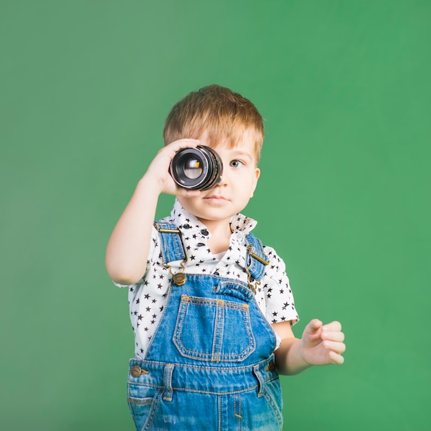 Free photo boy holding camera lens at eye