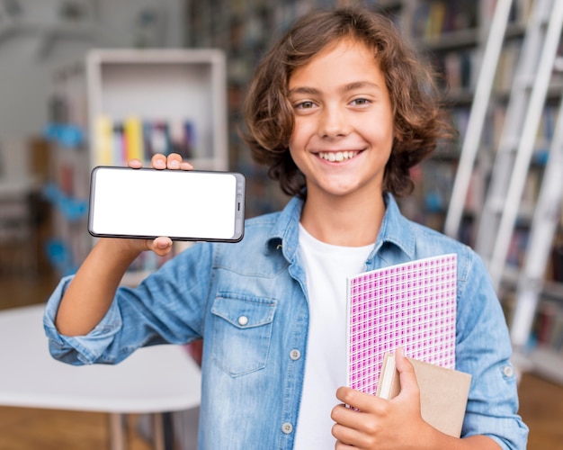 Boy holding an empty screen phone in the library