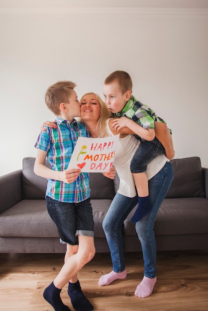 Boy holding a poster and kissing his mother