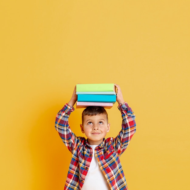 Boy holding stack of books on his head