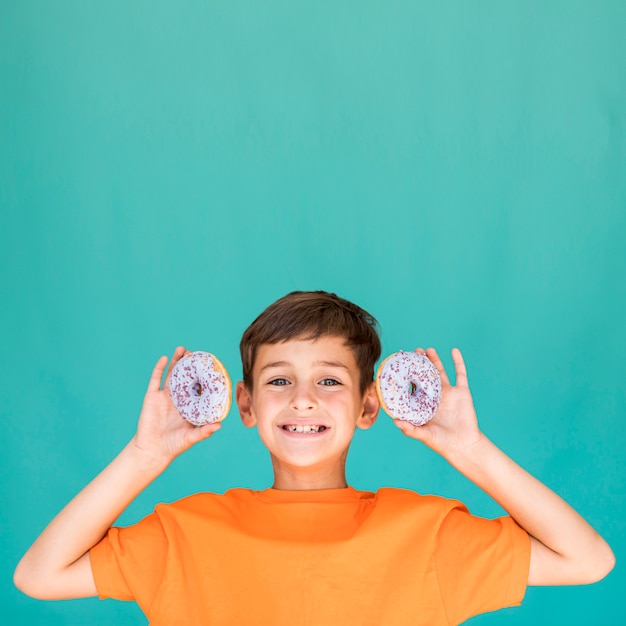 Boy holding two doughnuts with copy space