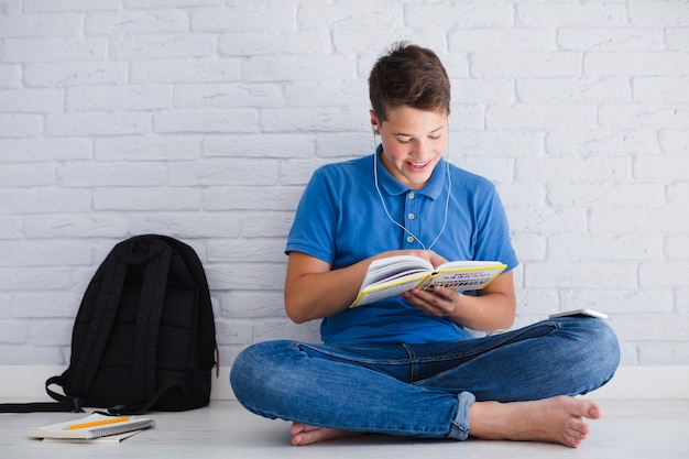 Free Photo boy listening to music and reading book