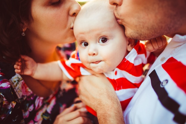 Boy looks funny while parents kiss his head