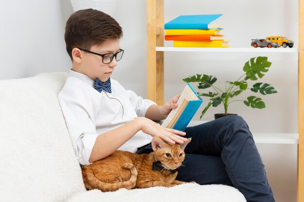 Boy petting cat and reading