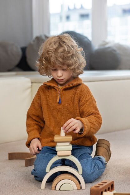 Free photo boy playing with eco toys indoors full shot