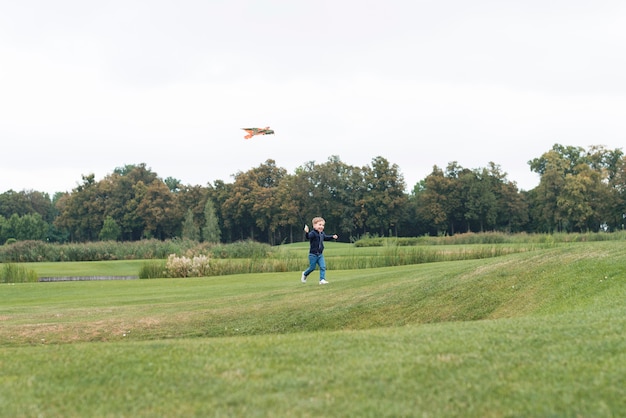 Free photo boy playing with kite long shot