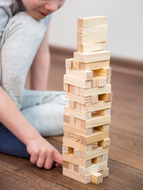 Boy playing with wooden tower game on the floor