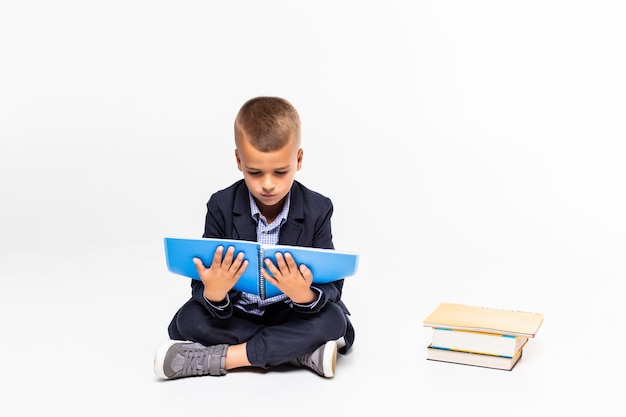 Free photo boy read book sitting on the floor on a white wall