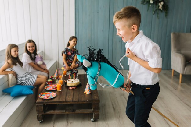 Boy riding hobby horse on birthday party