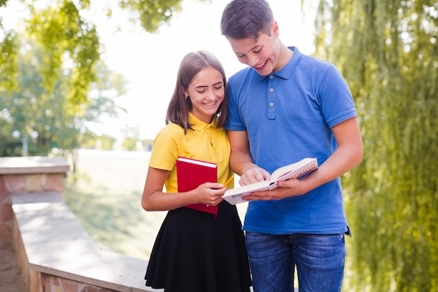 Boy showing to girl book in park