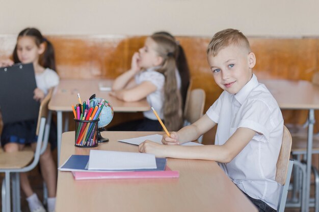 Boy sitting in classroom and writing