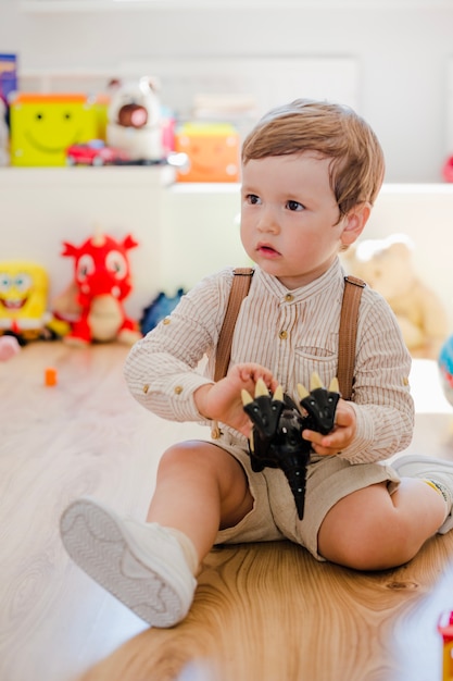 Free photo boy sitting playing with dinosaur toy