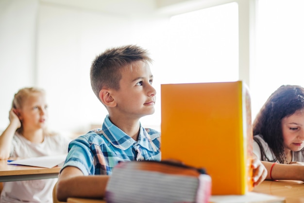 Boy sitting at school desk holding textbook