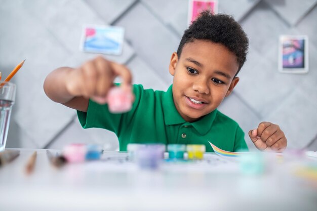 Boy sitting at table looking at paints with enthusiasm