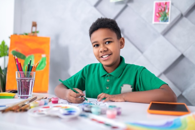 Free Photo boy sitting at table with pencil looking at camera