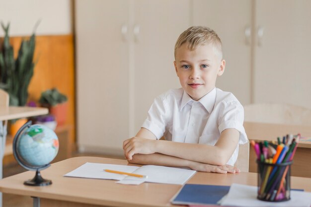 Boy sitting with hands on table in classroom