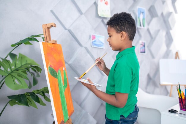 Boy standing near easel sideways to camera