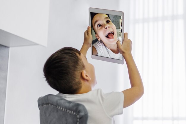 Boy taking a self portrait on digital tablet