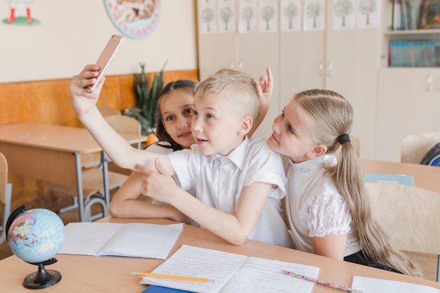 Free photo boy taking selfie with girls at desk