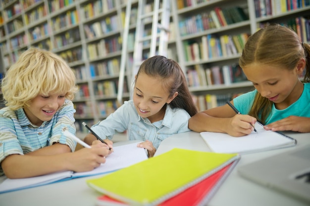 Free Photo boy and two girls writing at table